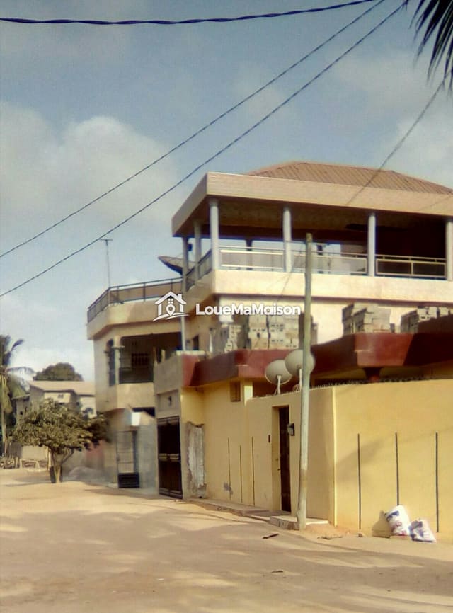 Maison jaune à étage avec terrasse couverte à Agoè
